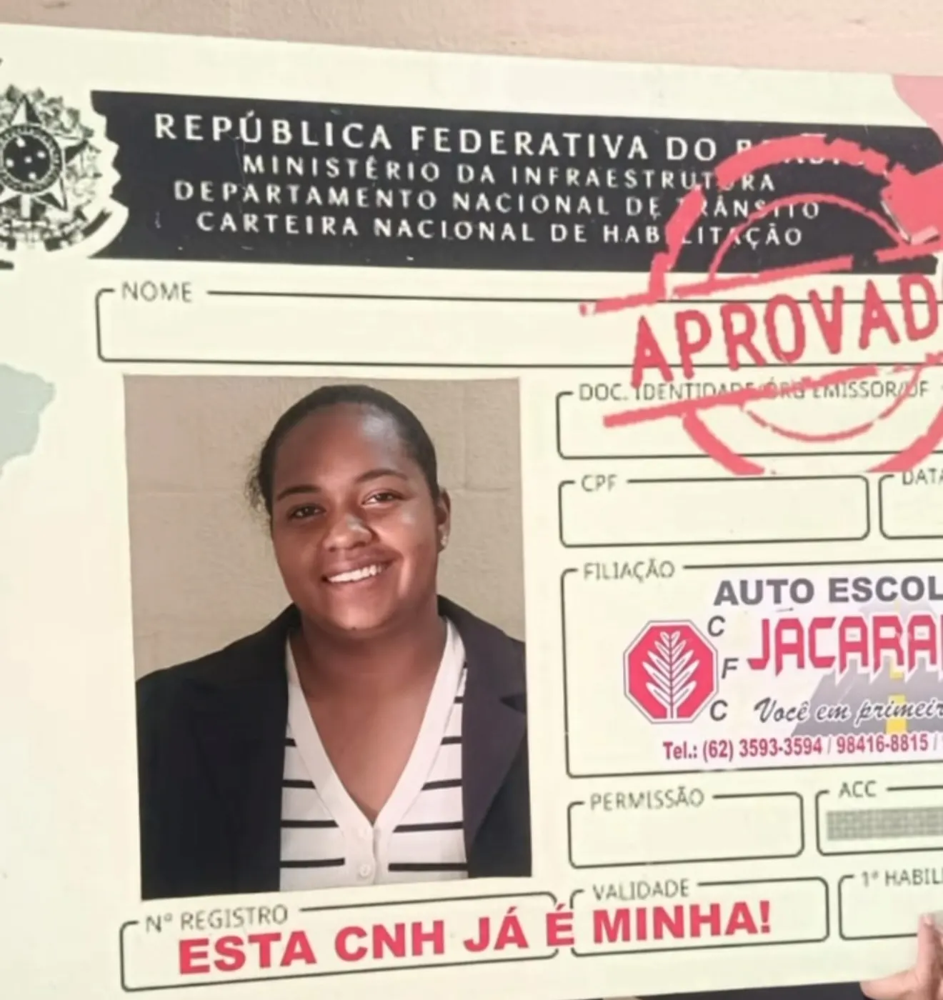 Aluna aprovada segurando a moldura Esta CNH já é minha
