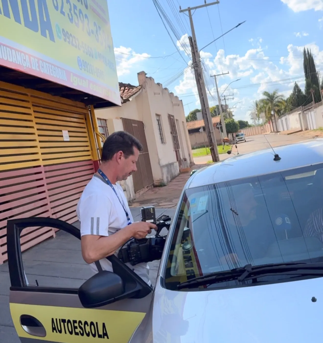 Instrutor da Jacarandá ao lado do carro de aulas, na frente da autoescola